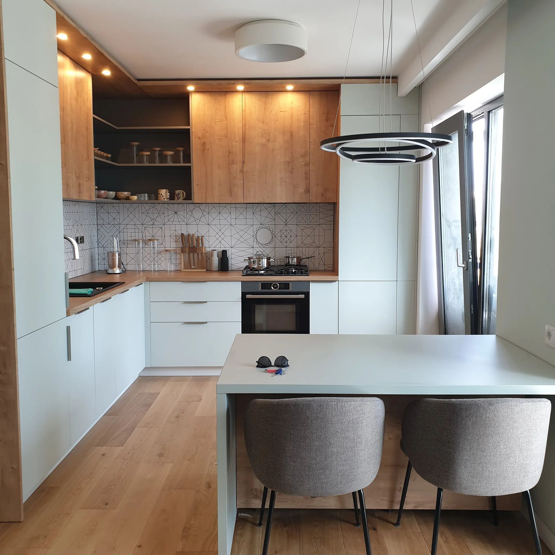 Bucătărie luminoasă în formă de L cu insulă și mobilier la comandă