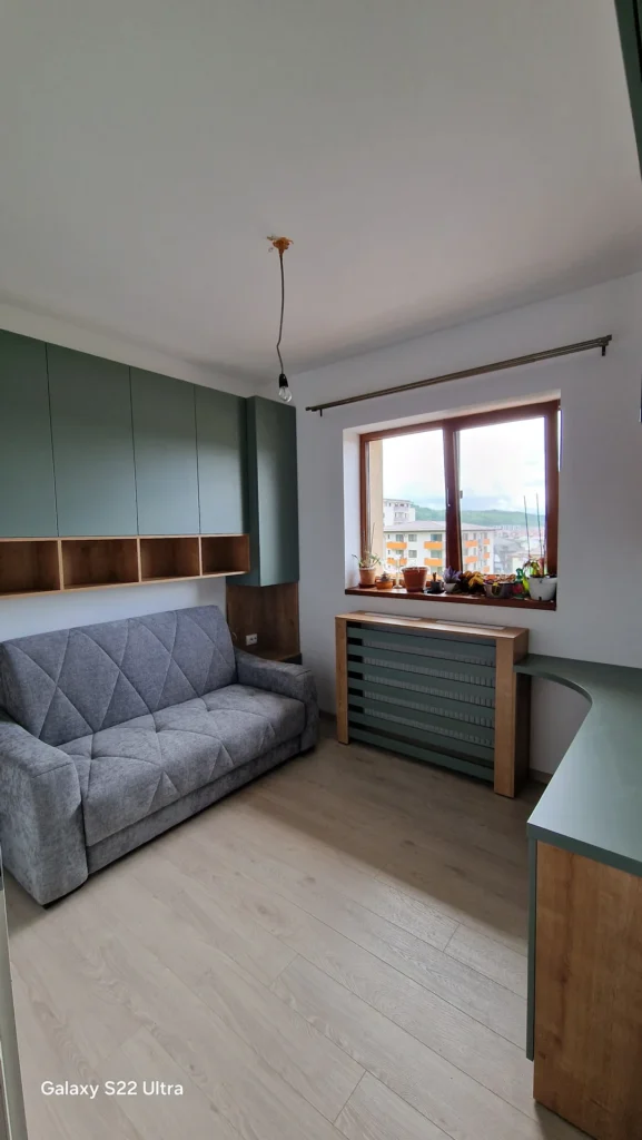 Vedere de ansamblu a camerei cu mobilier verde și birou la comandă