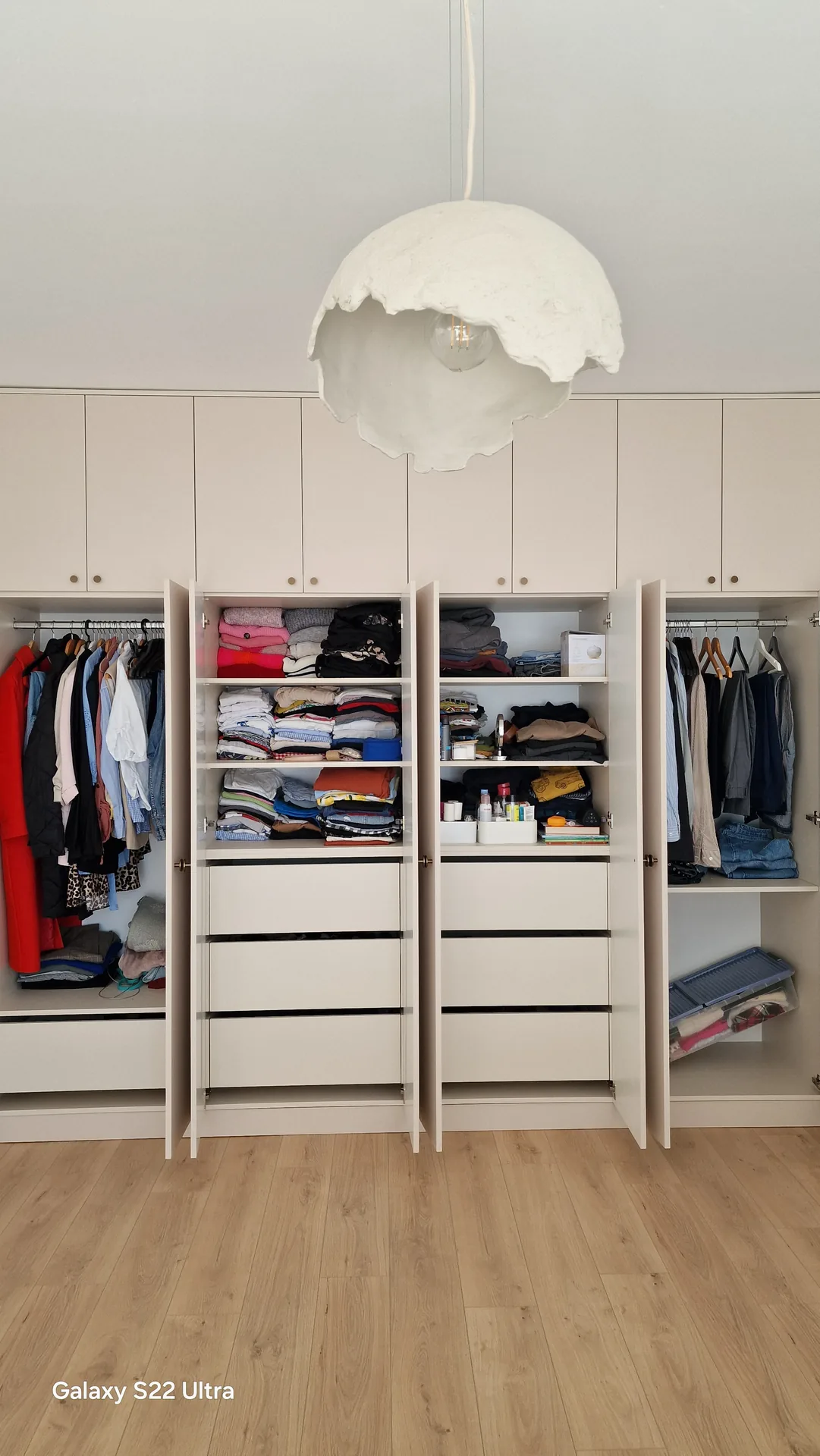 Interior organizat de dressing alb cu sertare și bare pentru haine